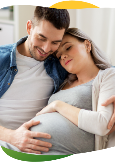 A pregnant woman suffering from bloating, sitting on the sofa with her eyes closed. Her partner comforts her and holds her in his arms